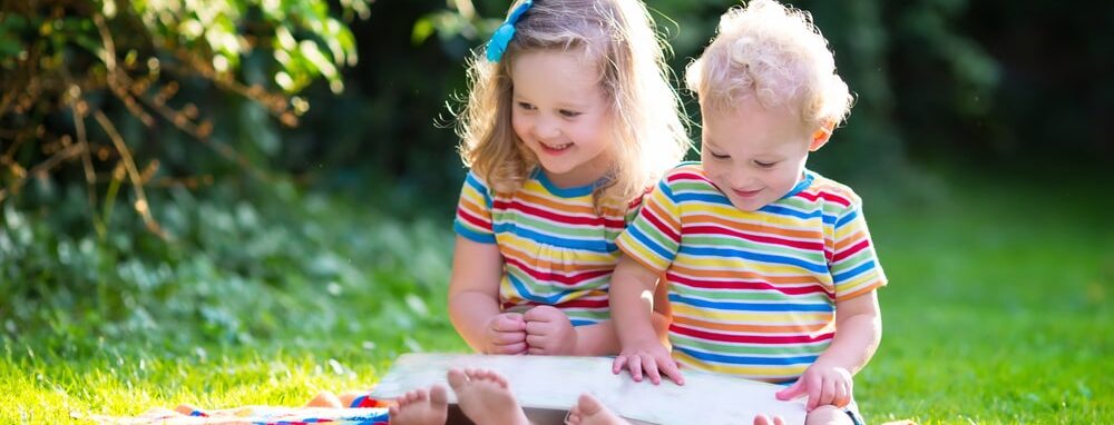 Kinder sitzen auf dem Rasen