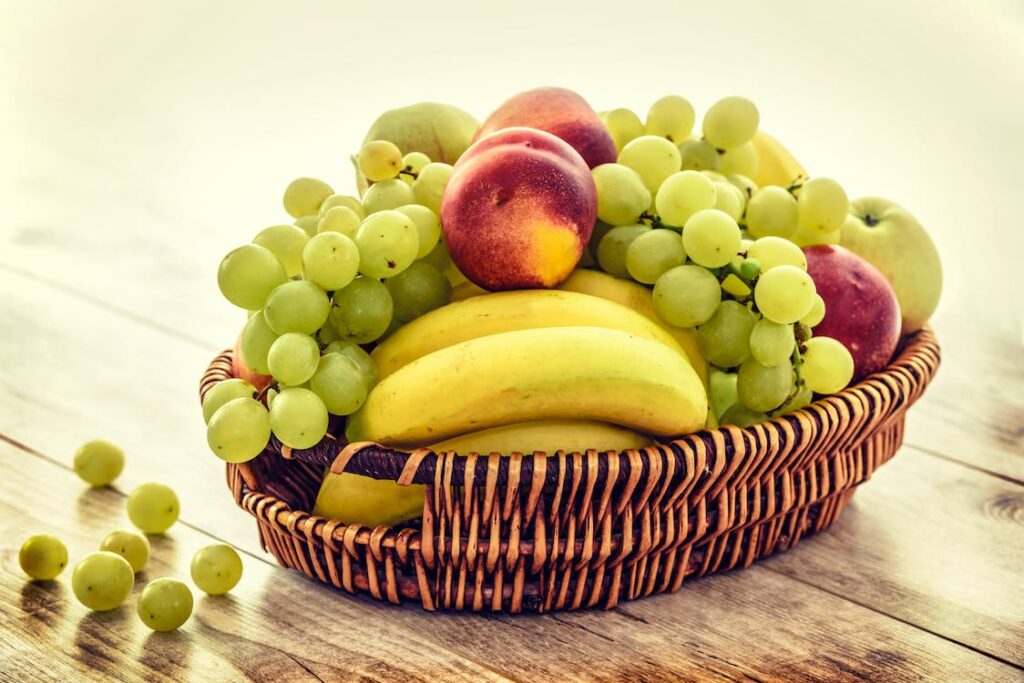 Ein Obstkorb mit frischen Bananen, Trauben und Äpfeln.