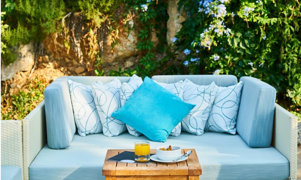 Eine blaue Couch mit blauen Kissen in einem Garten mit Südausrichtung.